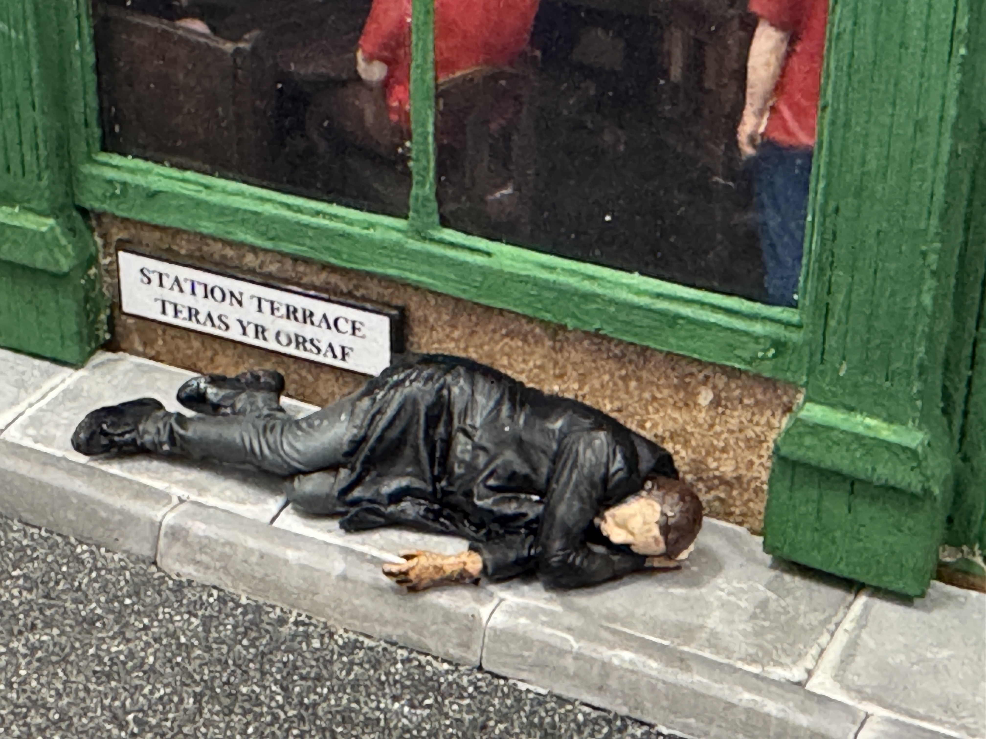 Man lying down on the pavement outside The Railway Tavern, Cwm Bach